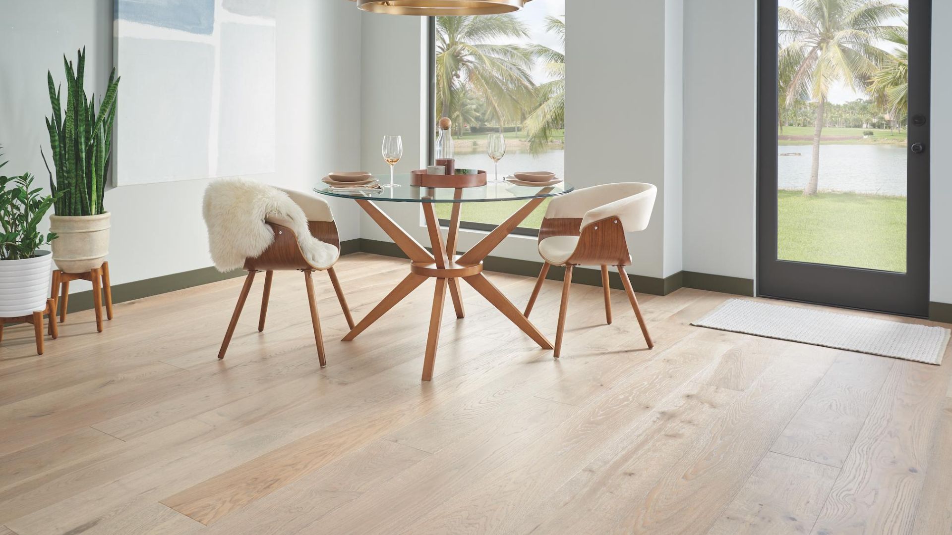 light toned hardwood flooring in a bright dining room with glass table and large windows